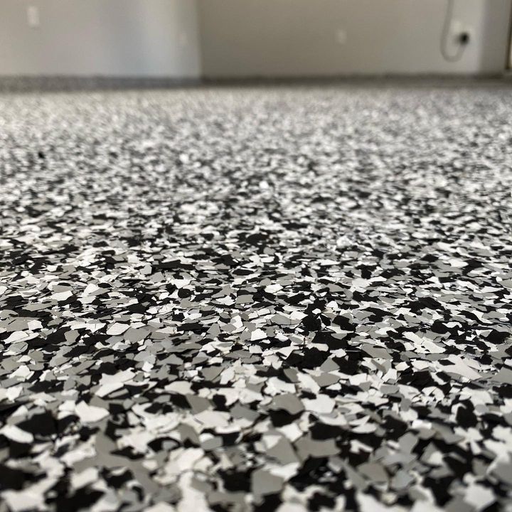 Close-up of a speckled flooring pattern with black, gray, and white chips; likely a garage or similar room.