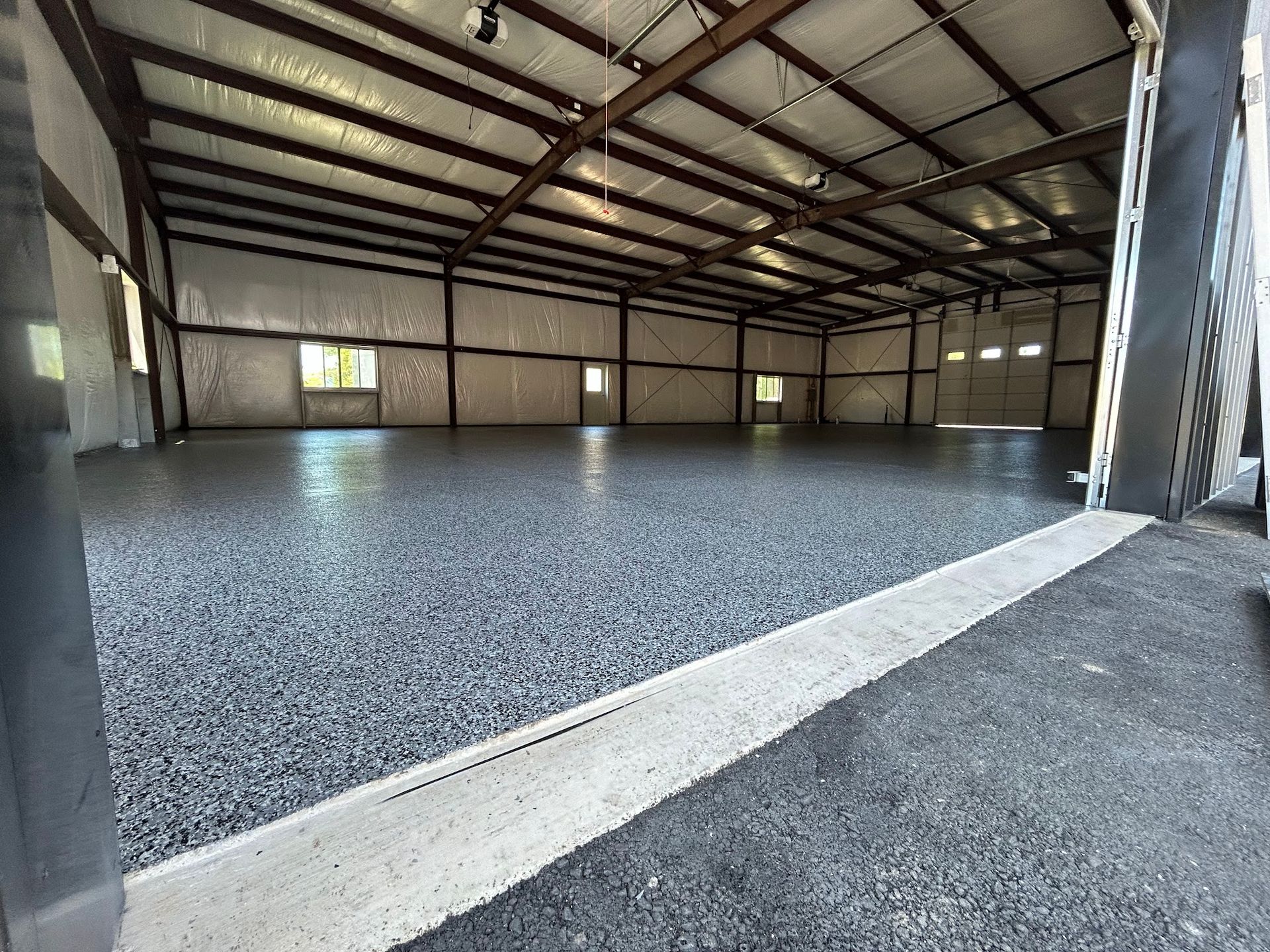 Spacious industrial interior with dark gray epoxy floor and exposed steel beams.