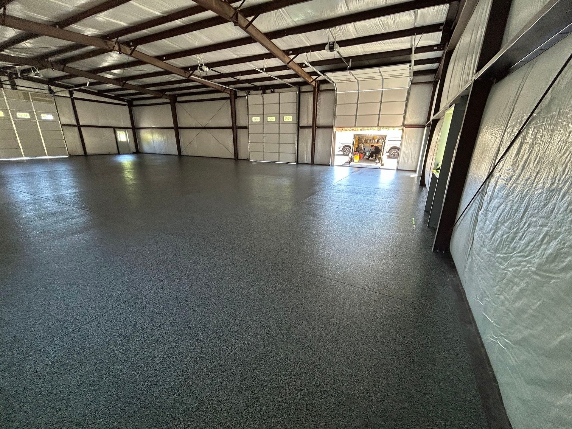 Spacious interior of a steel-framed warehouse with a polished, speckled gray floor.