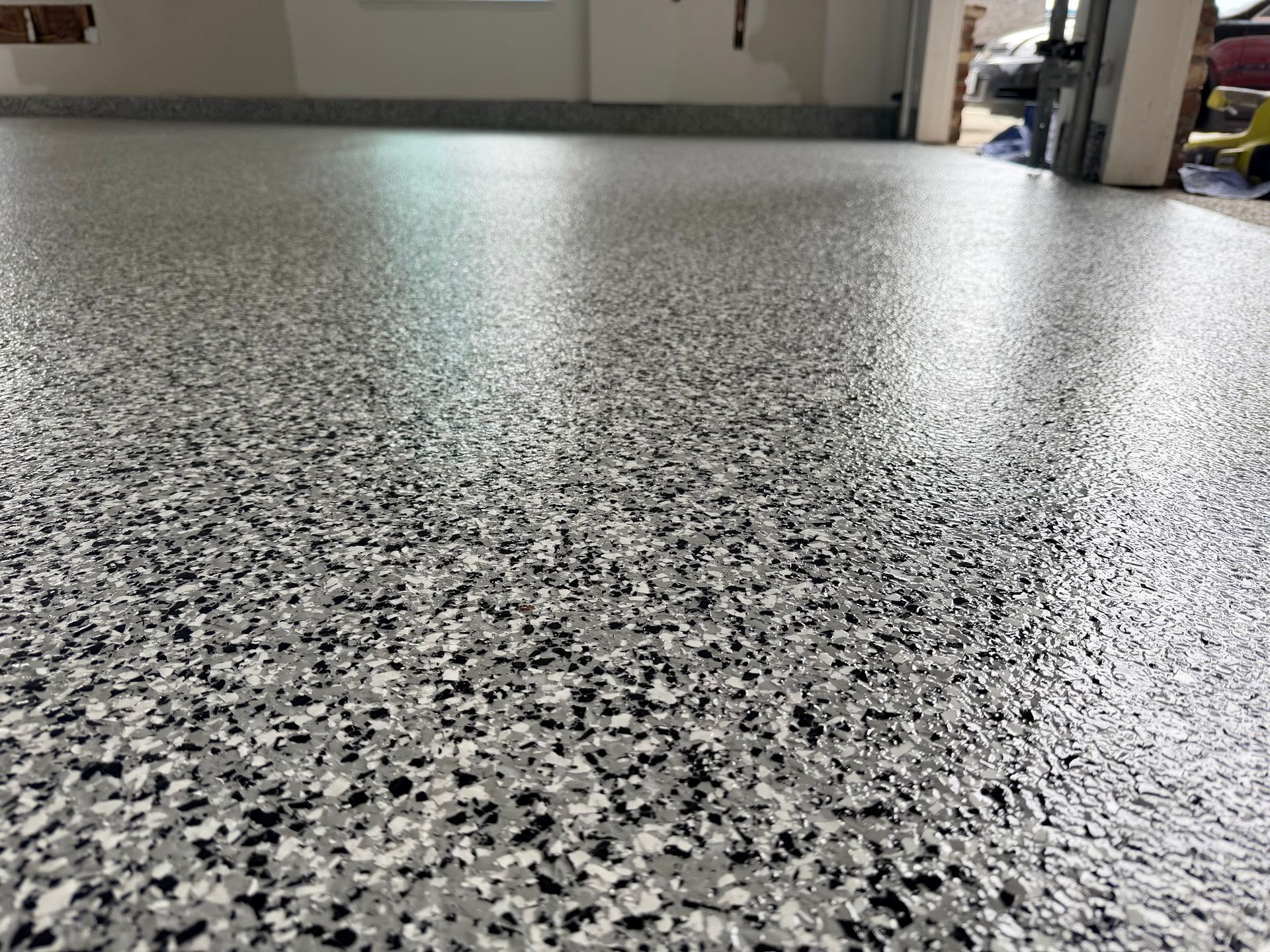 Close-up of a speckled, glossy epoxy garage floor in shades of gray, black, and white.