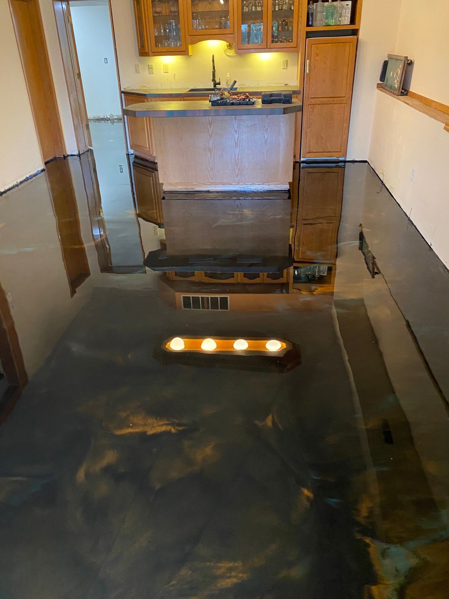 Metallic epoxy floor reflects a kitchen with wood cabinets, gold and black hues.
