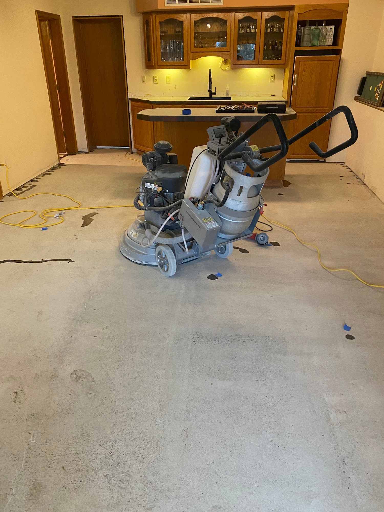 Floor grinding machine in a kitchen, preparing concrete surface for new flooring.