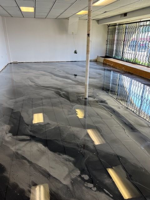 Metallic epoxy floor in an empty commercial space with white walls and a security gate.