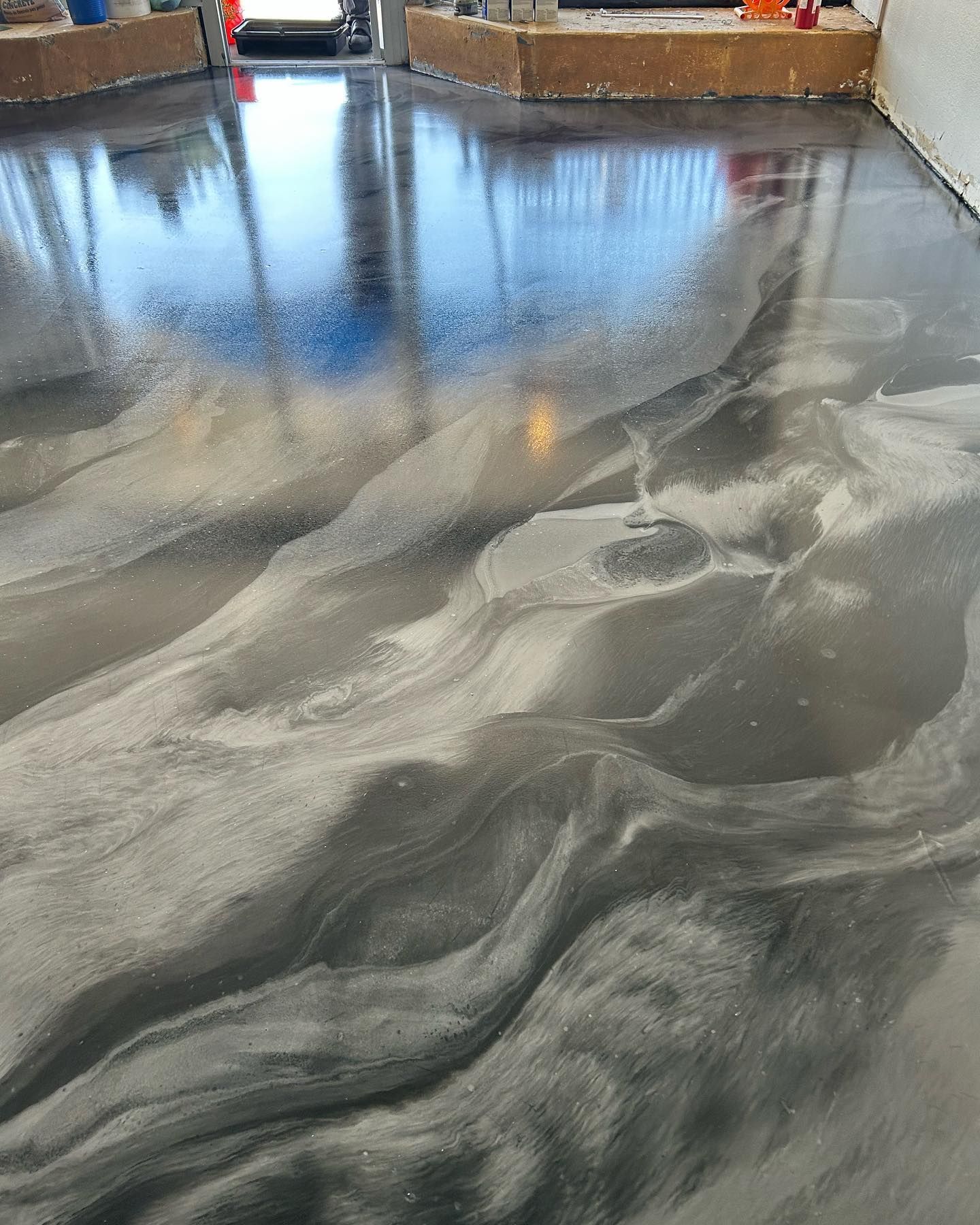 Metallic epoxy floor with silver and gray swirling design, reflecting light.