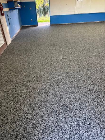 Room with speckled gray flooring, blue and white walls, and a doorway to the outside.