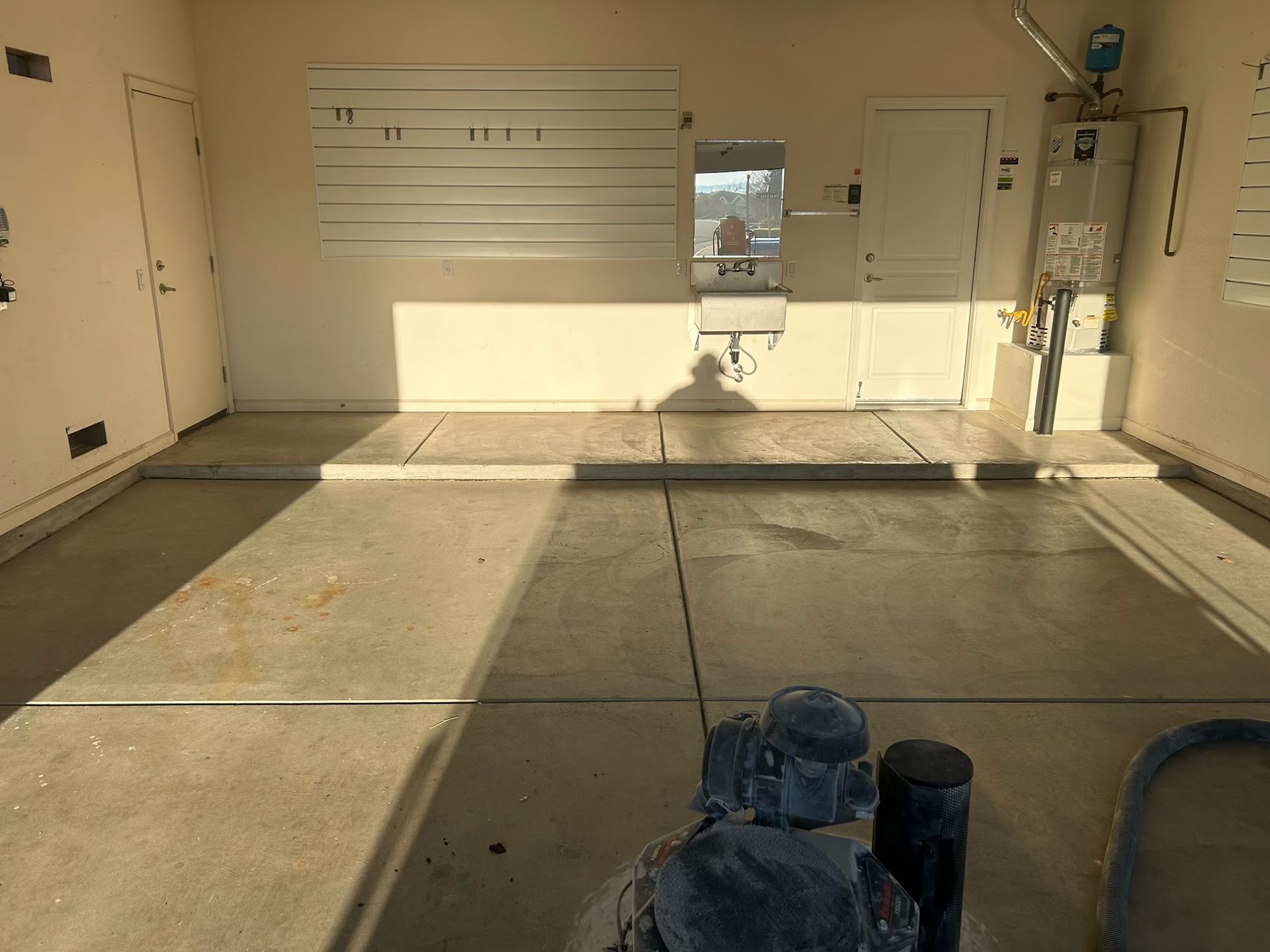 Empty garage interior with concrete floor, white walls, and a partially open garage door.