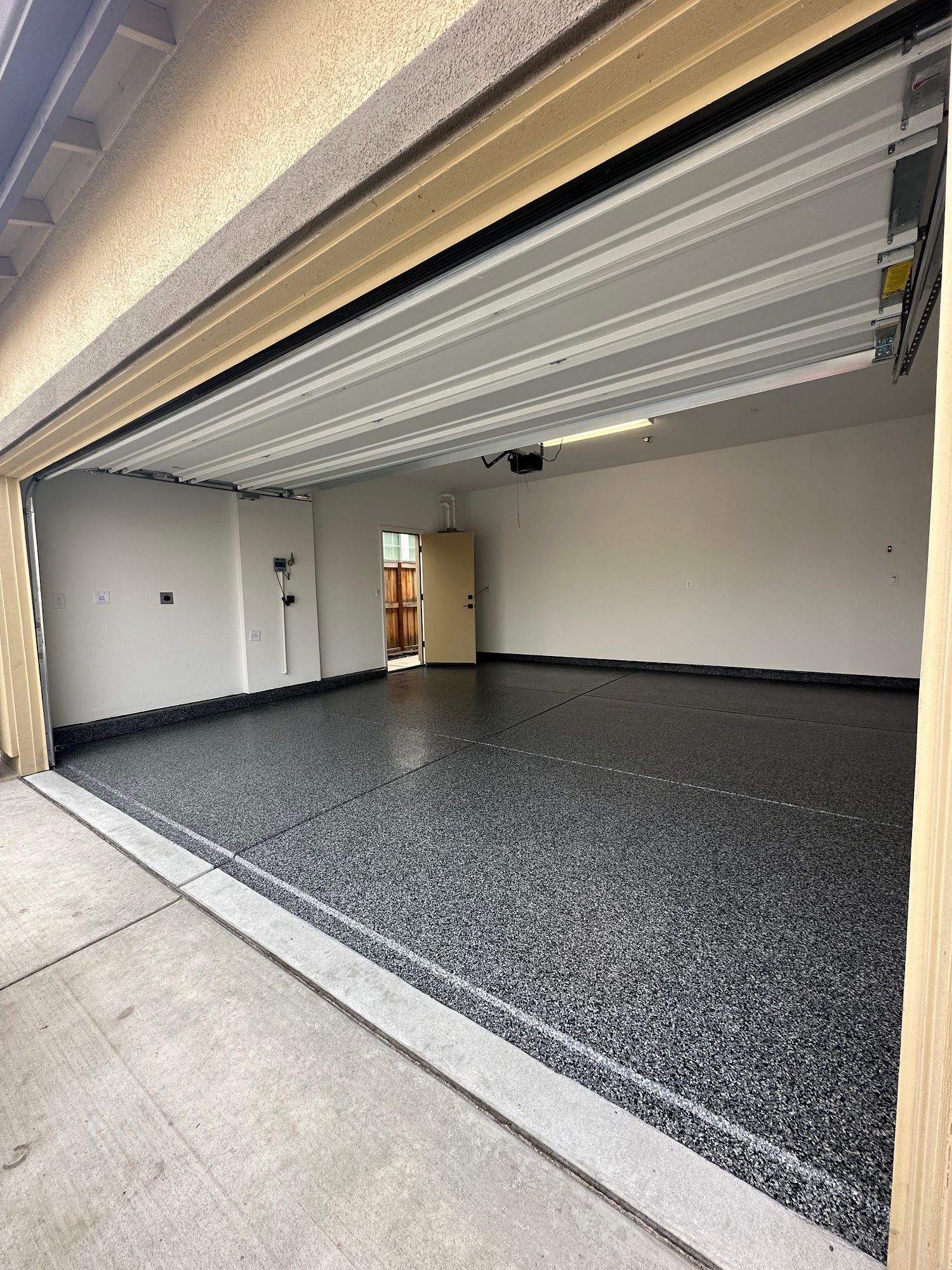 Open garage with new gray epoxy floor; white walls and ceiling.