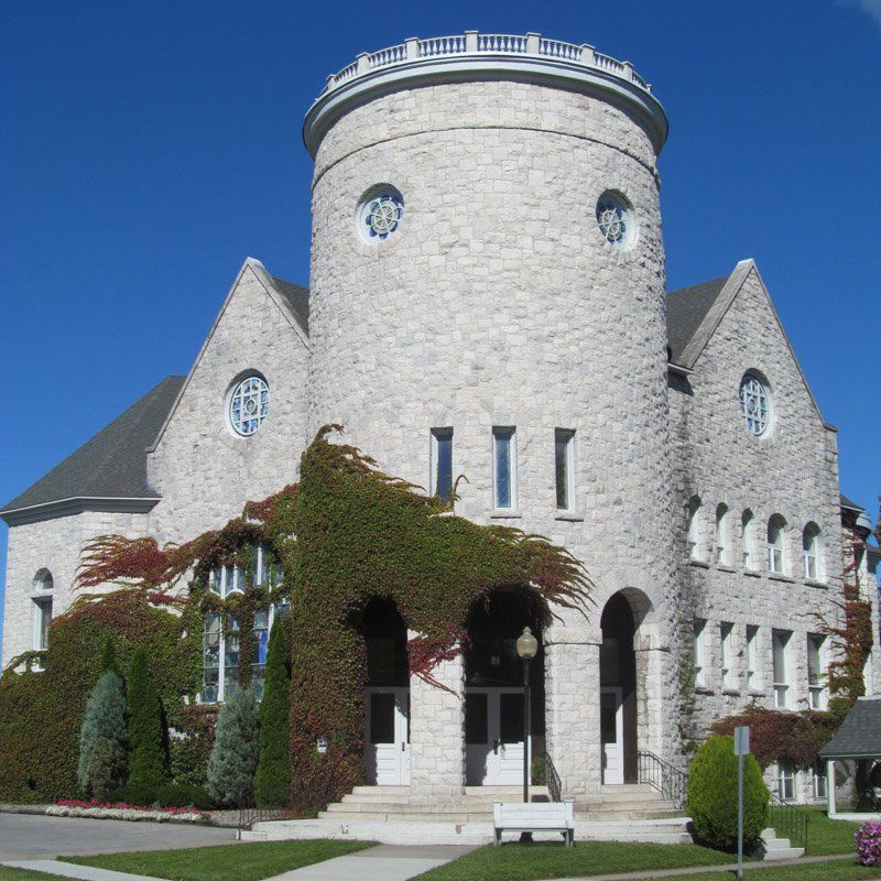 Stone church with a tall tower, ivy, and a blue sky.