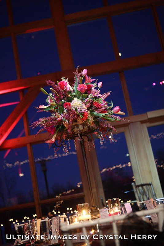 Tall floral centerpiece with pink and red blooms at a reception.
