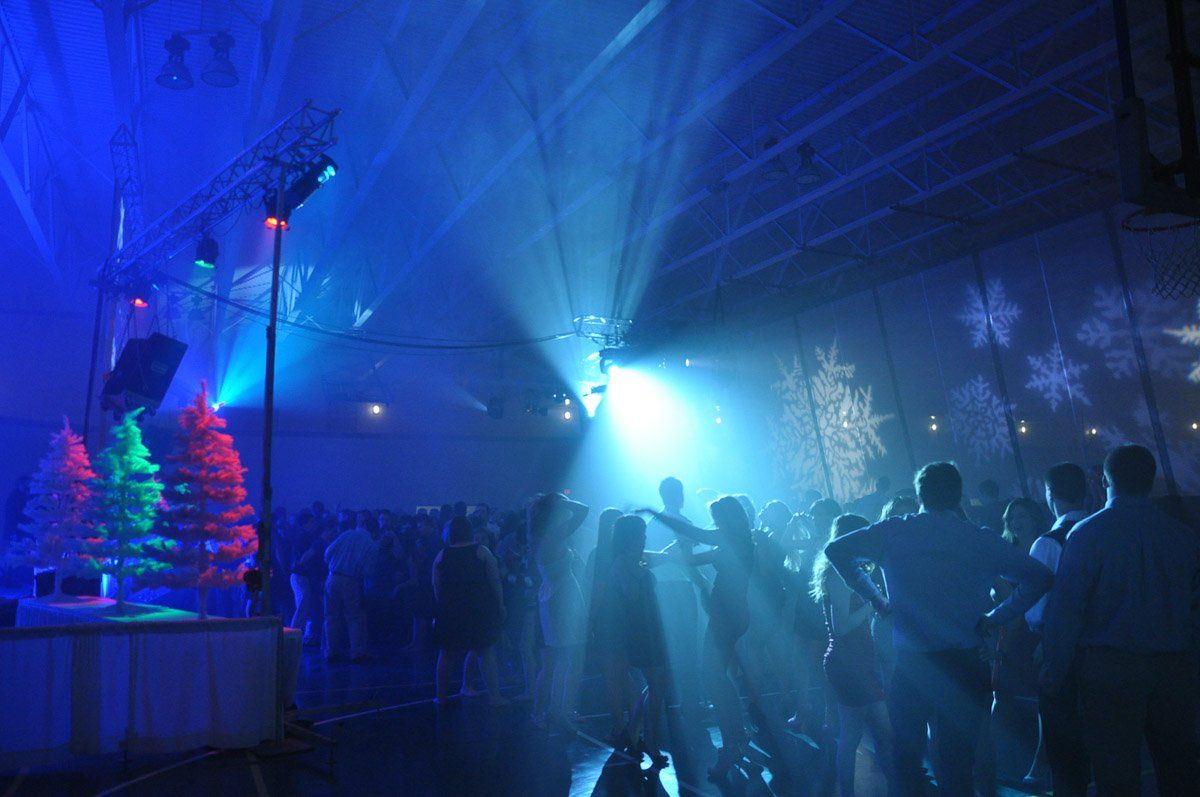 Party with blue lighting; silhouettes of people dancing, snowflakes, Christmas trees.