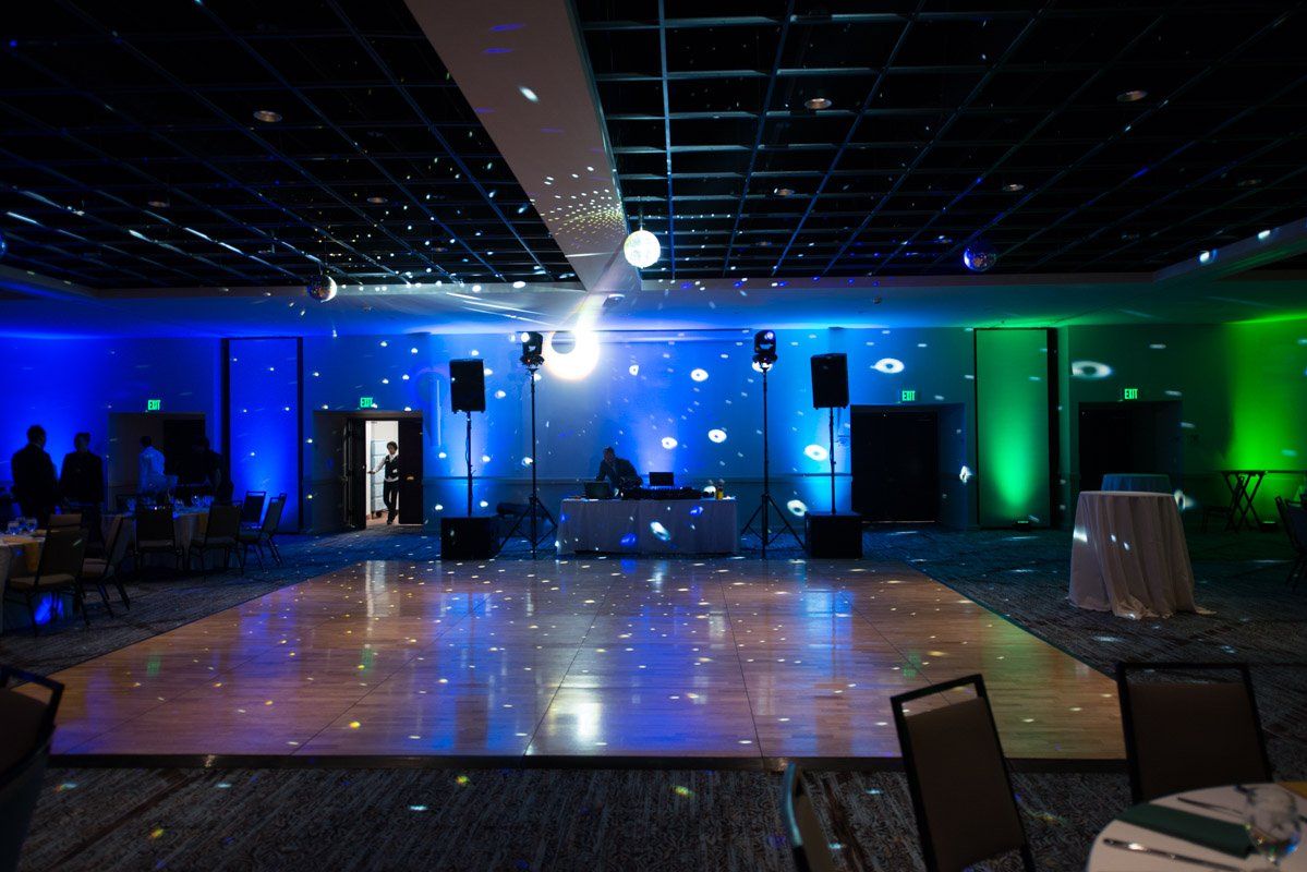 Dance floor in a room with DJ setup and colorful lights.