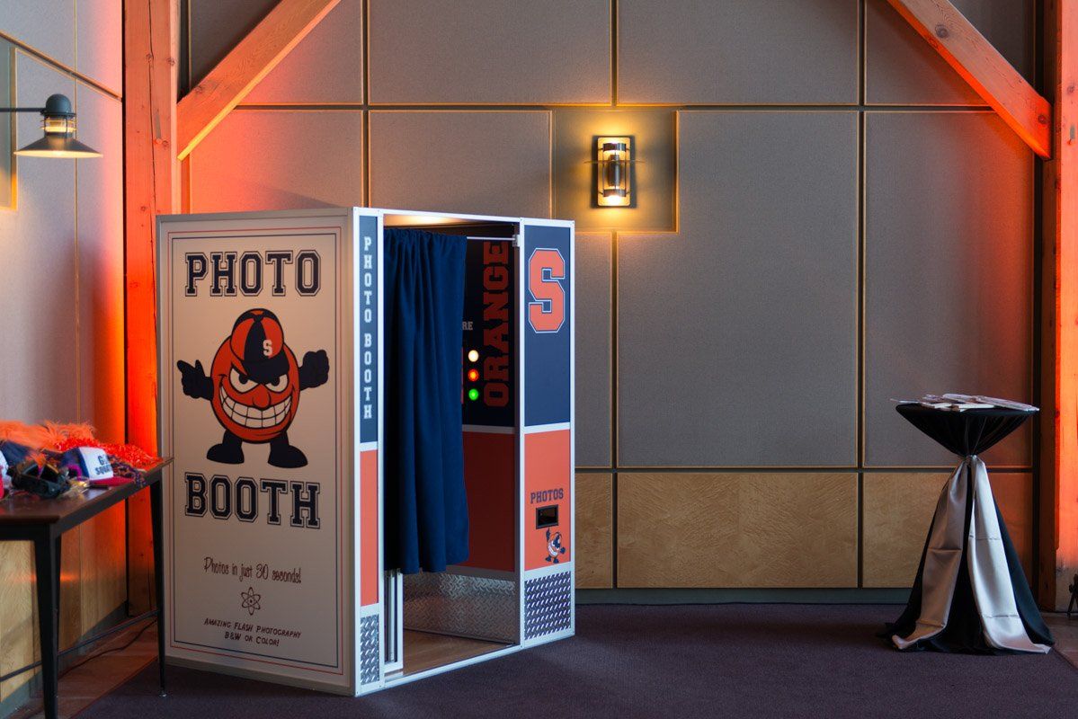 Photo booth with Syracuse Orange branding in a wood-paneled room.