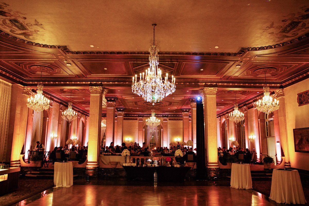Elegant ballroom with chandeliers, gold accents, and a gathering.
