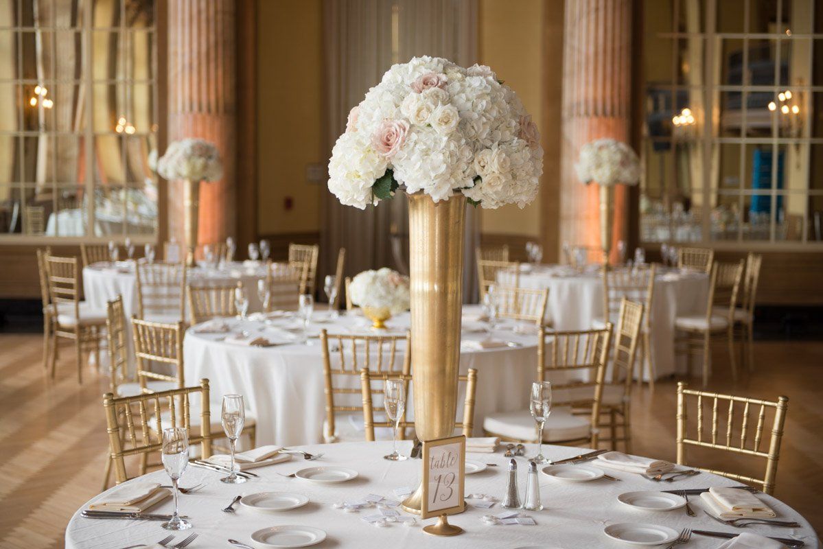 Elegant wedding reception with gold accents and floral centerpieces.