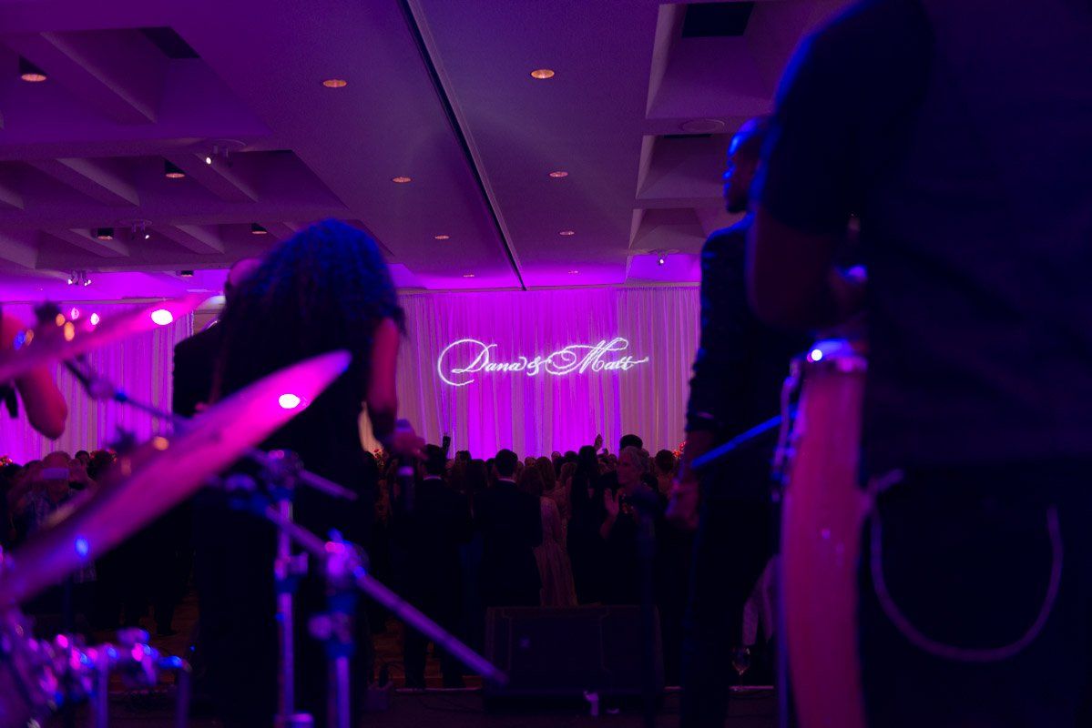 Band performing at a venue with a neon sign that says 