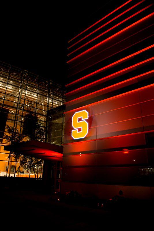 Orange and dark building at night with a large orange 