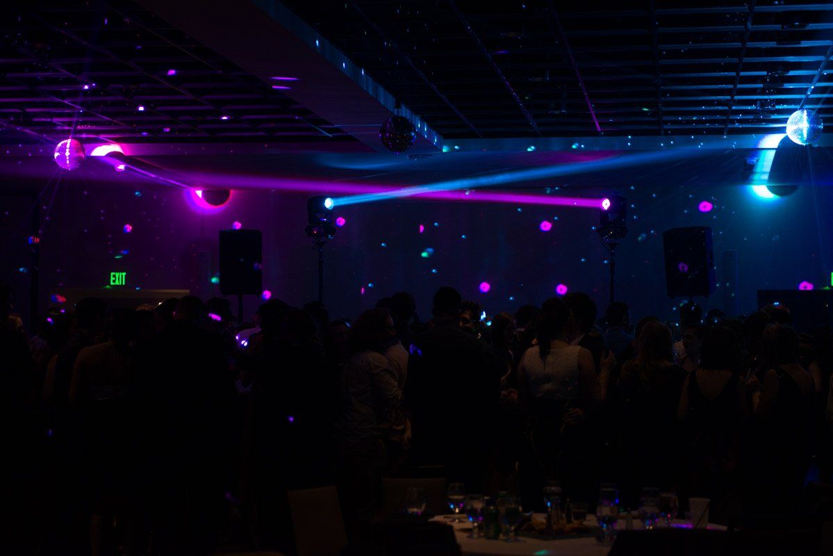 Dance floor with purple and blue stage lights illuminating a crowd in a dark room.