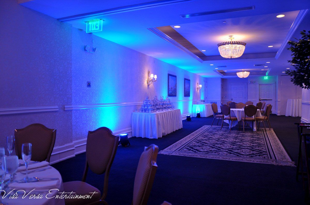 Blue-lit banquet hall with tables, chairs, and a champagne fountain.