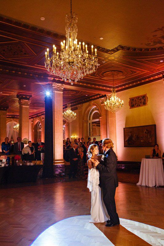 Bride and groom dance under a chandelier at a wedding reception.