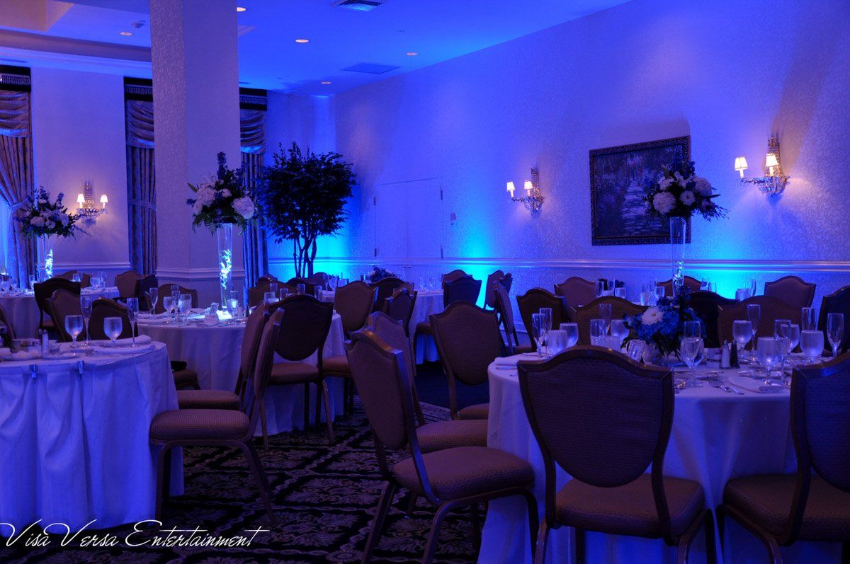 Elegant banquet hall illuminated with blue up-lighting. Tables set for a formal event.