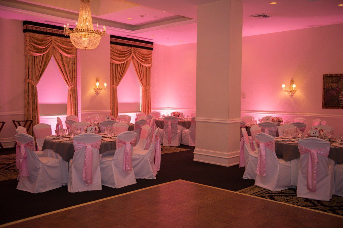 Banquet hall with pink lighting, round tables set for a formal event.
