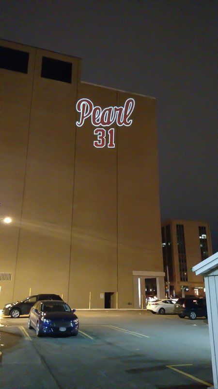 Pearl 31 illuminated sign on a building, with cars parked in front at night.