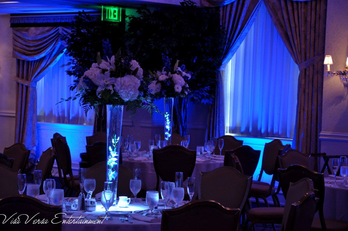 Elegant wedding reception tables with blue lighting and floral centerpieces.