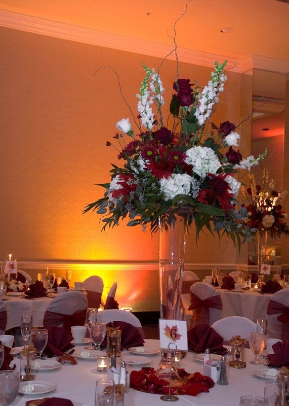 Elegant floral centerpiece with burgundy and white flowers on a wedding table.