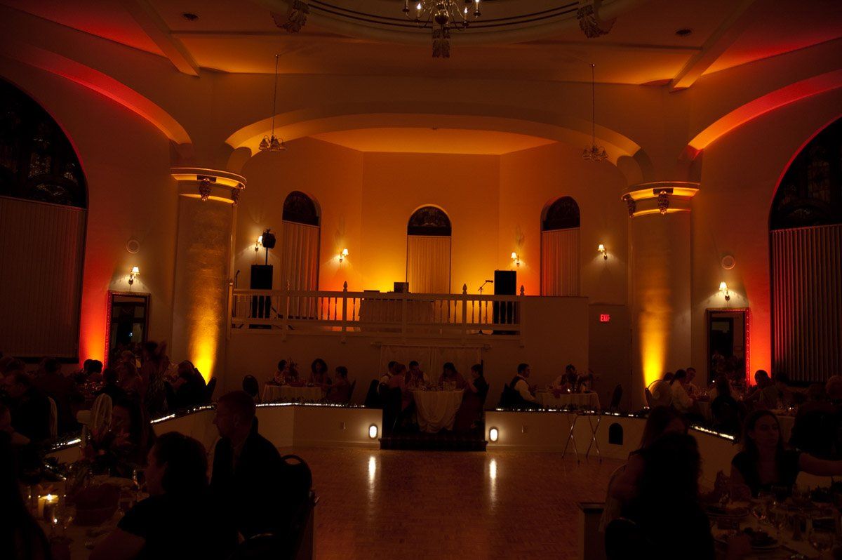 Elegant ballroom, orange lighting, wedding reception in progress.