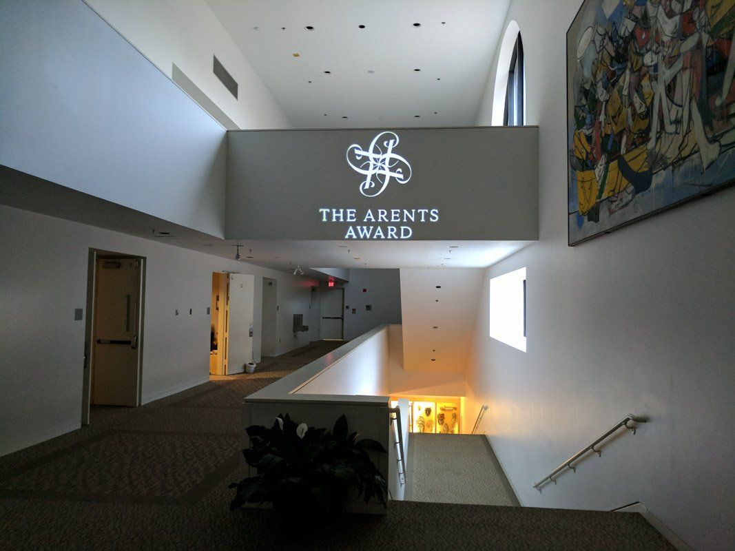 Hallway with The Agents Awards logo projected on a rectangular structure, with stairs and a painting on the right.