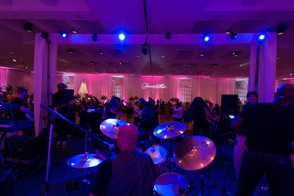 Band performing on stage at event with pink and blue lighting.