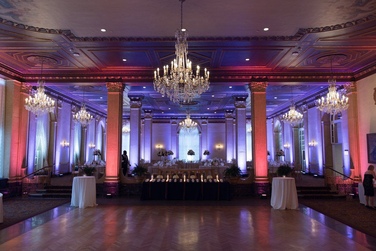 Elegant ballroom with crystal chandeliers, up-lighting, and tables set for an event.