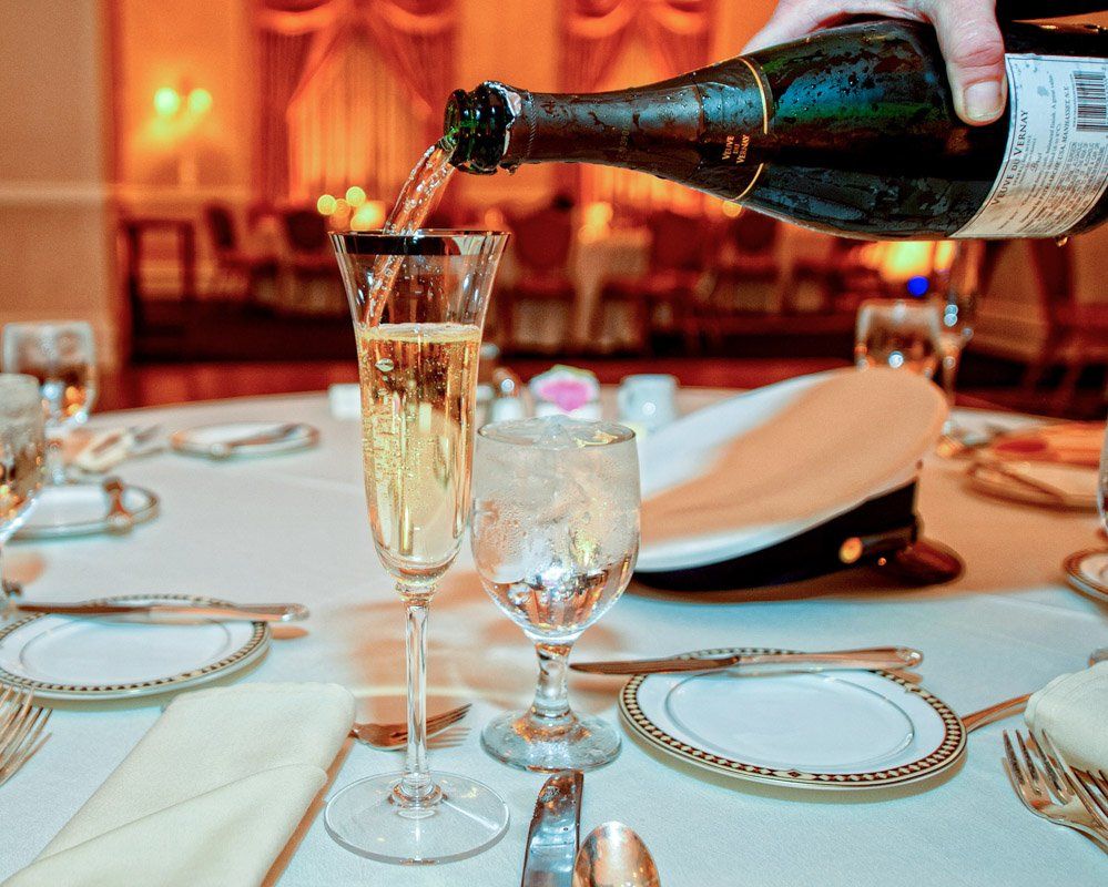 Champagne being poured into a flute at a formal dining table.