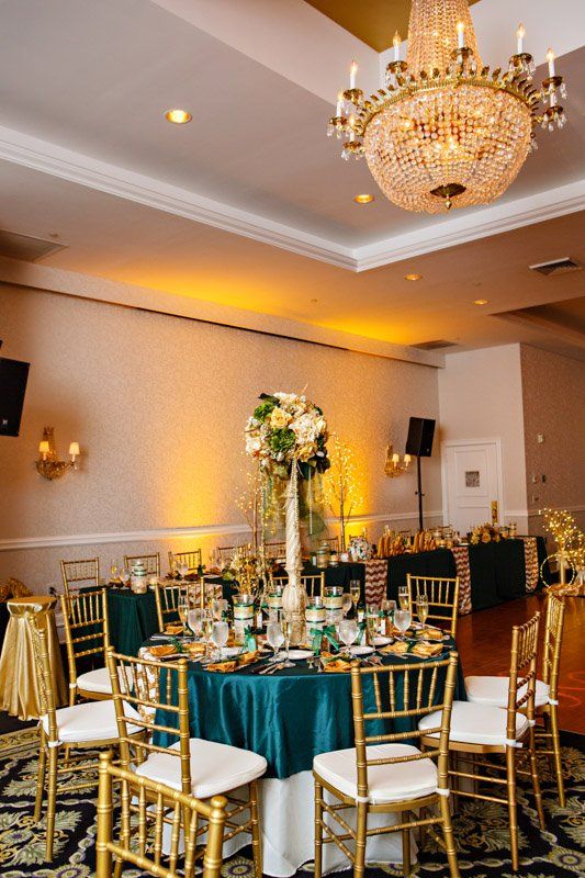 Formal dining area, teal table settings, gold chairs, and a chandelier.