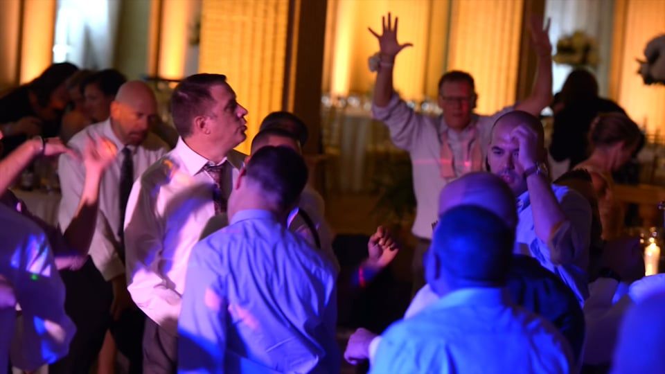 People dancing at a party under colorful lights; some have hands raised in the air.