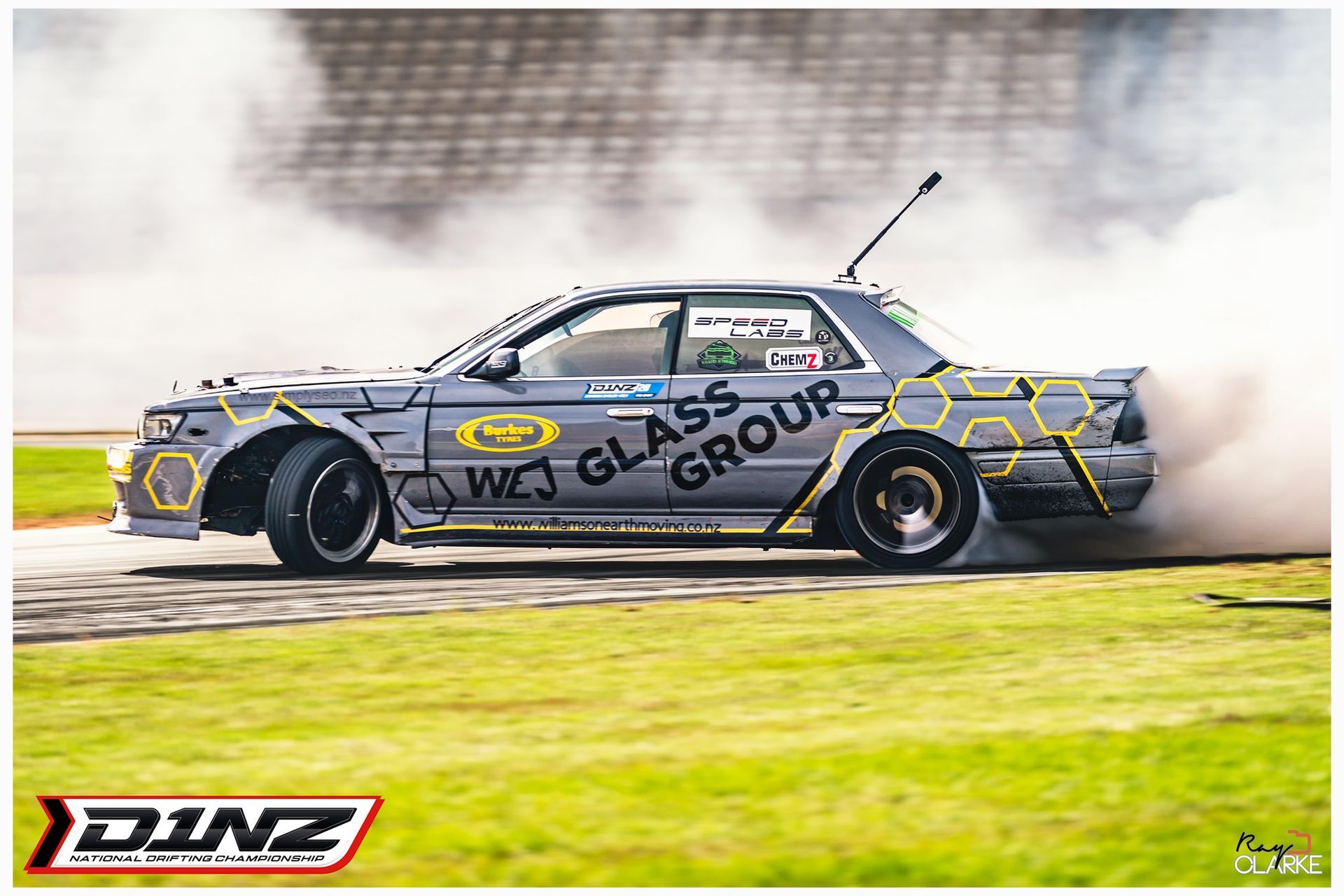 A car is drifting on a track with smoke coming out of the tires.