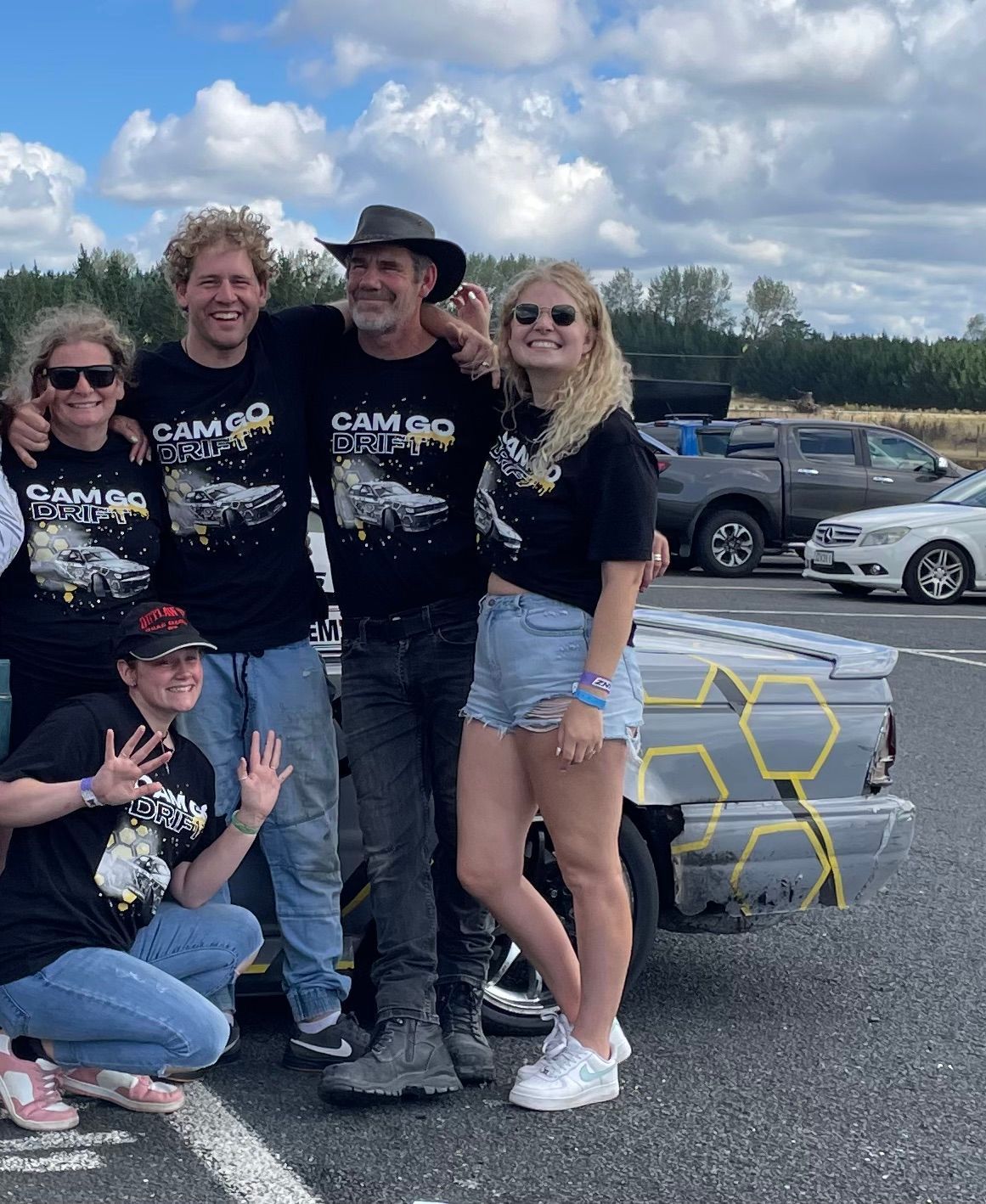 A group of people are posing for a picture in front of a truck.