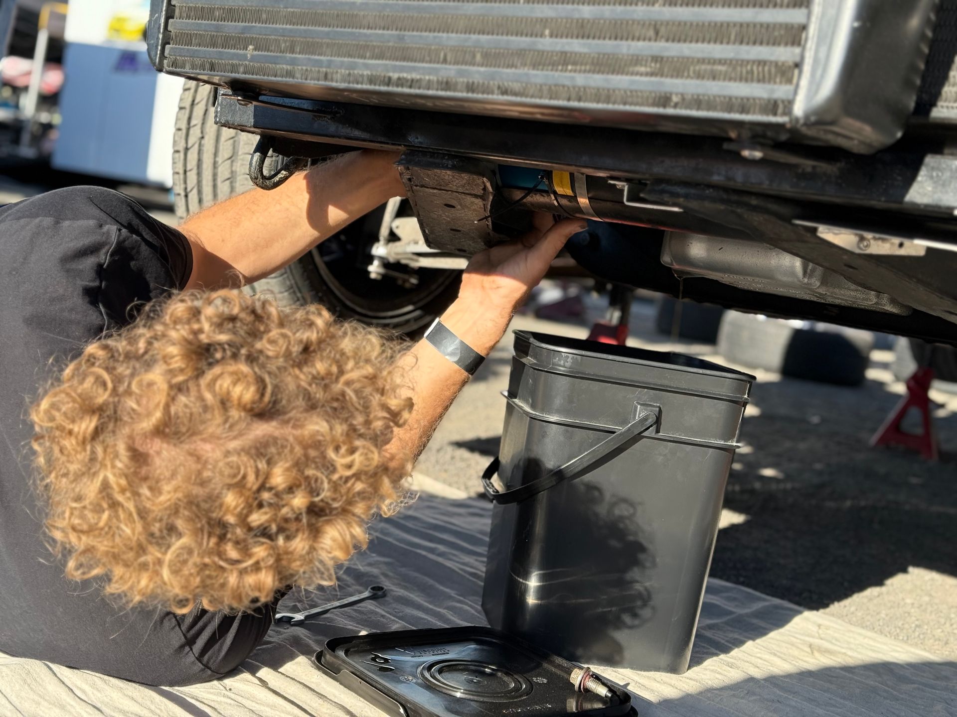 A man is laying on the ground working on a car.
