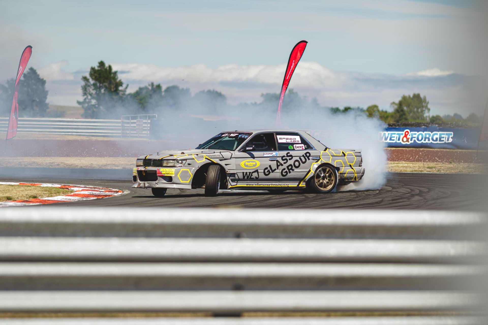 A car is drifting on a race track with smoke coming out of the tires.
