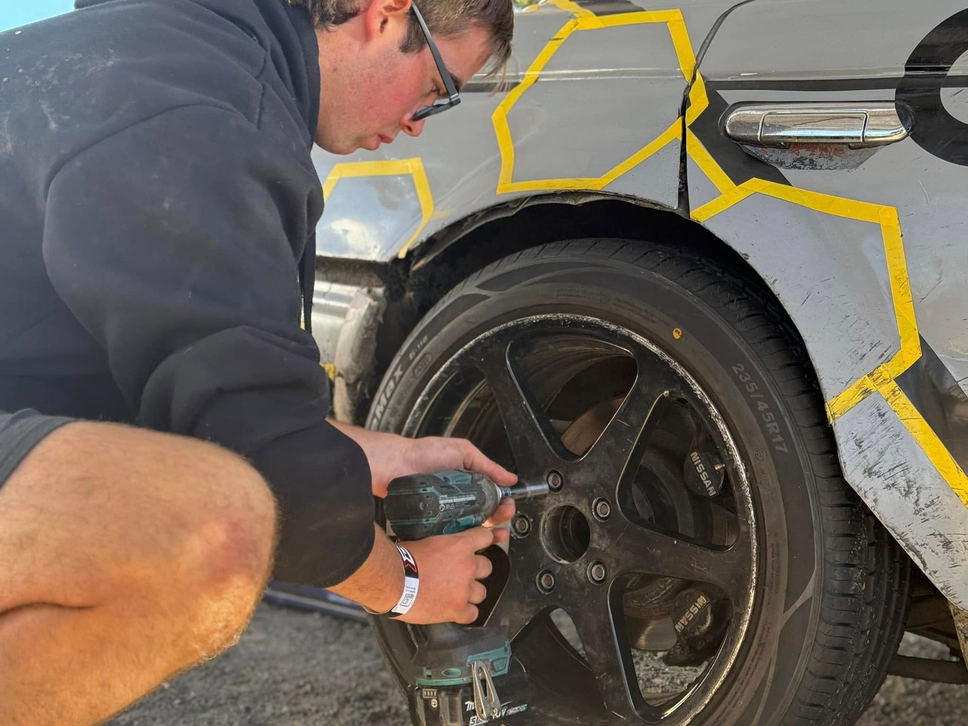 A man is working on a car wheel with a drill