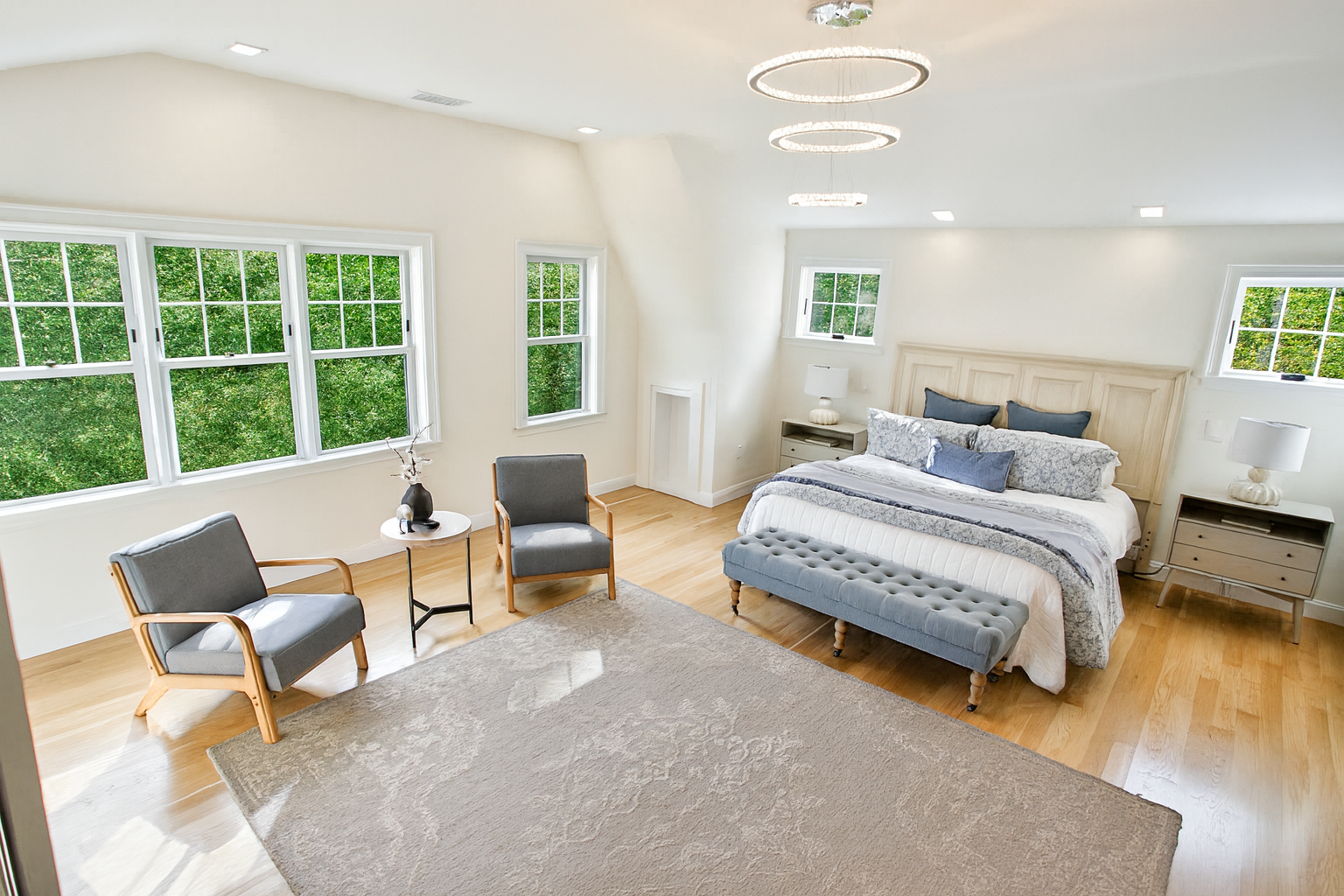 A large bedroom with a king size bed , chairs , and a rug.