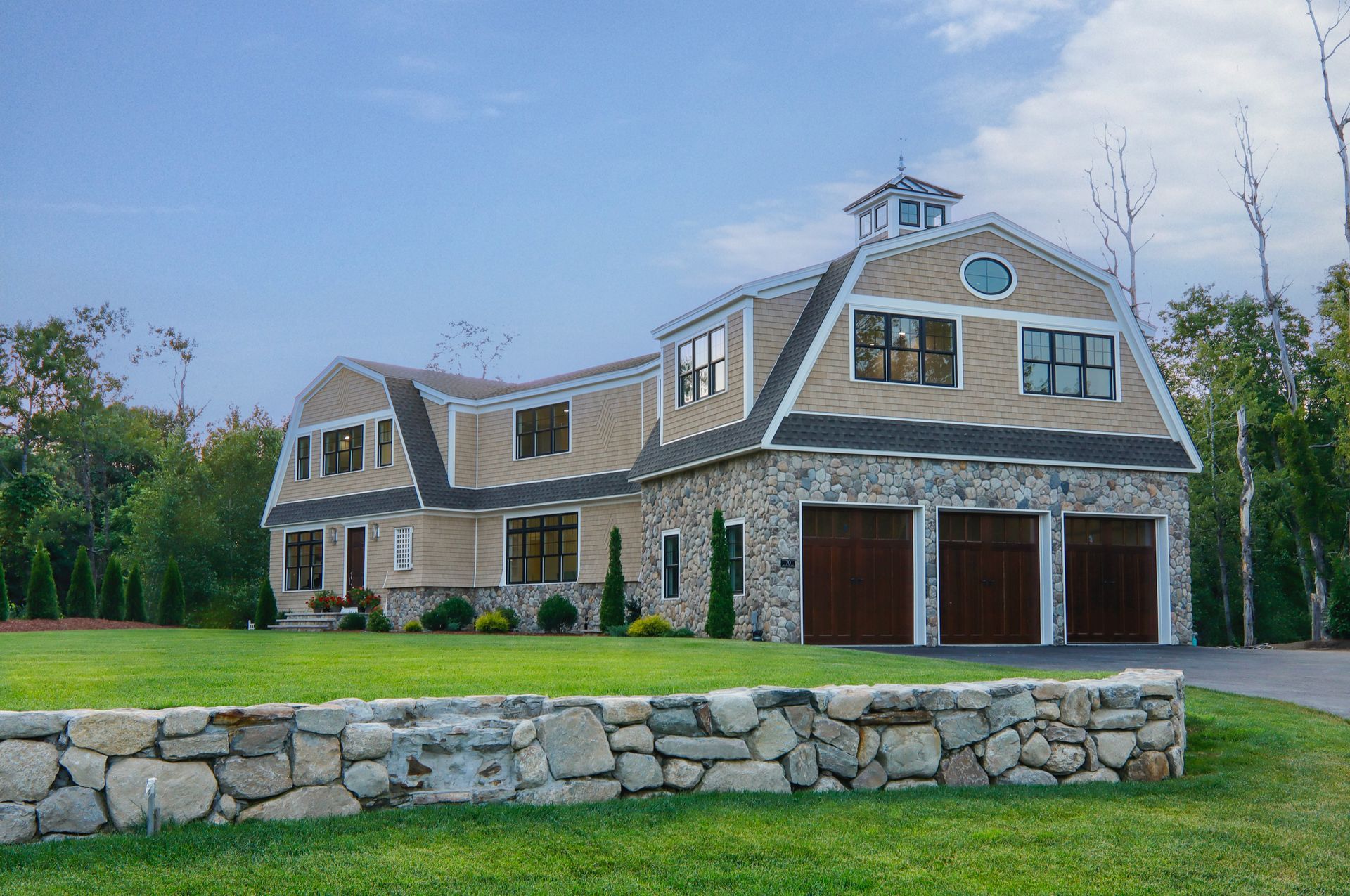 A large house with a stone wall in front of it.