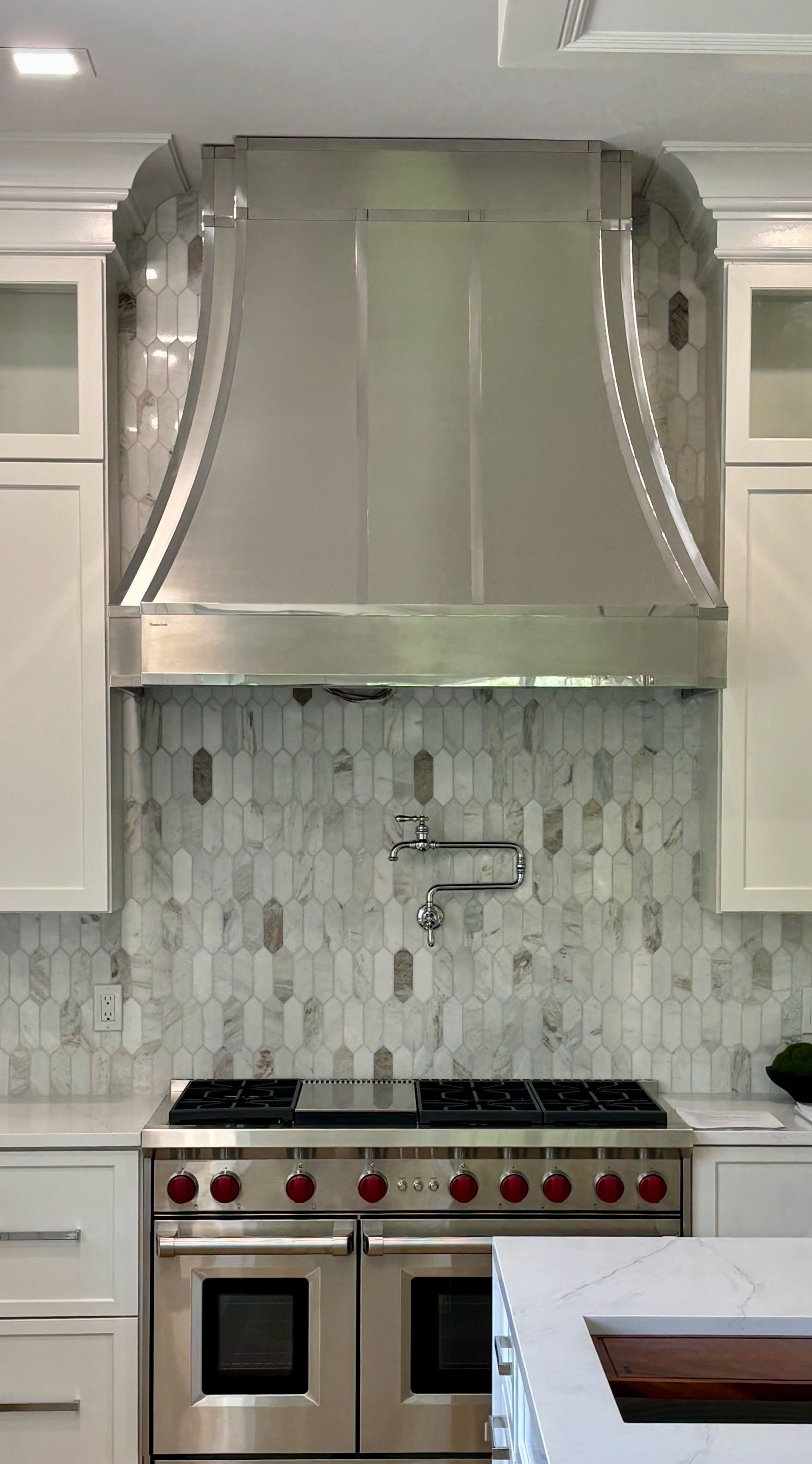A kitchen with a stove top oven and a stainless steel hood.
