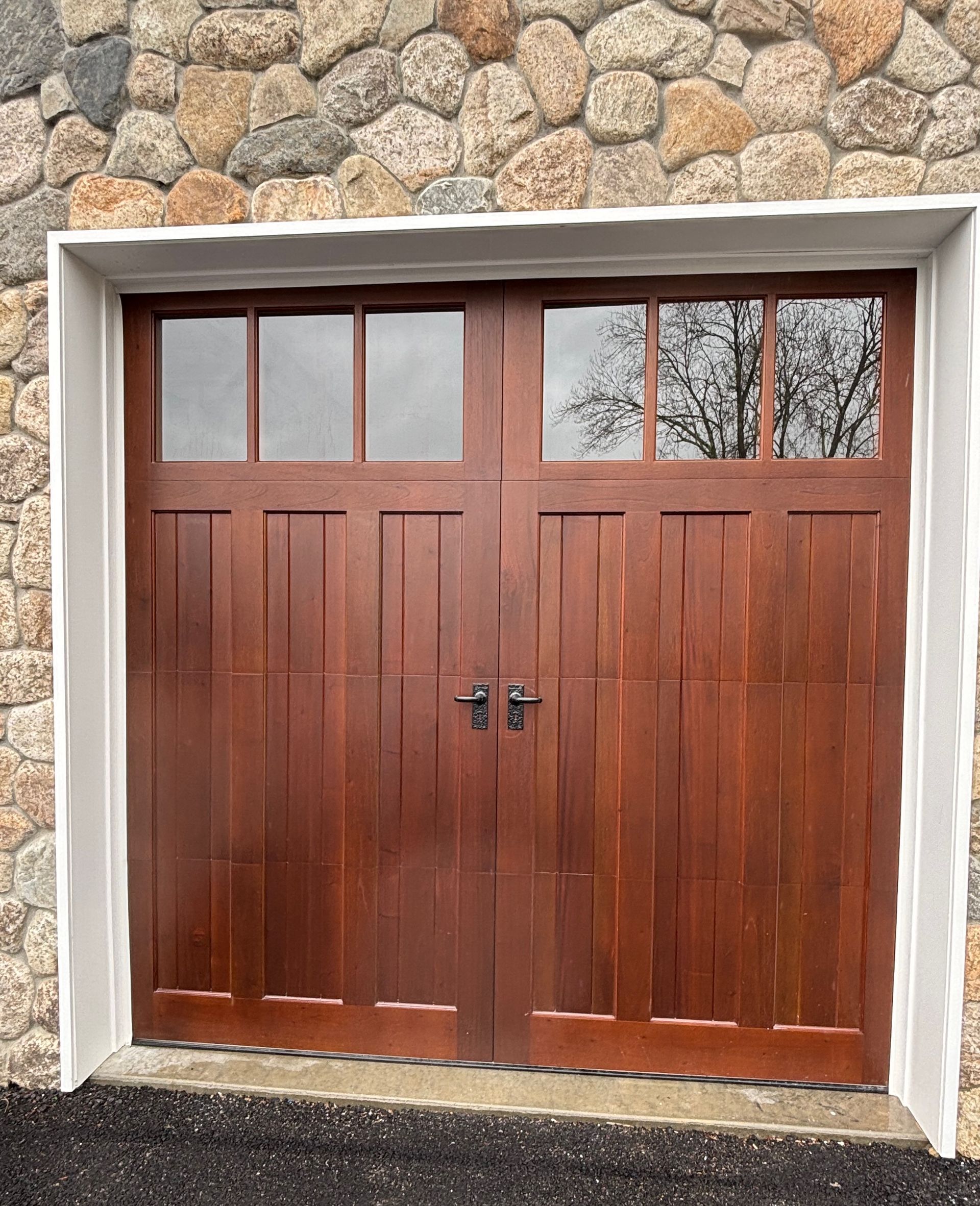 A wooden garage door is sitting in front of a stone wall.