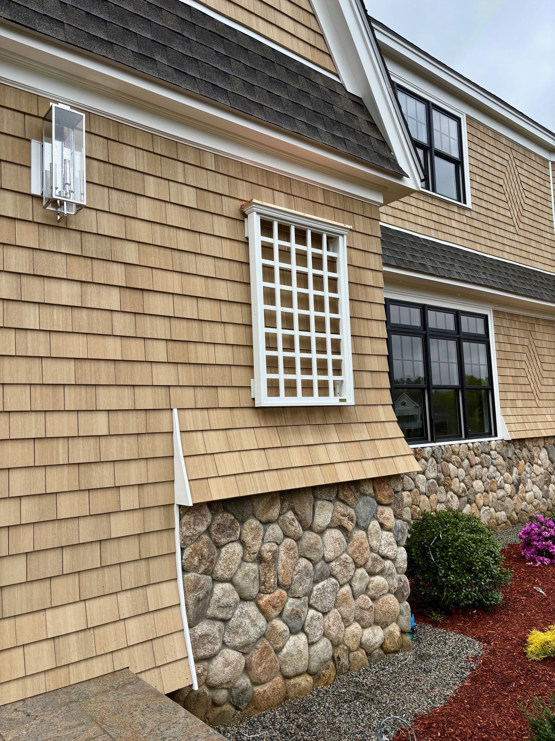 A large house with a stone wall and a wooden siding.