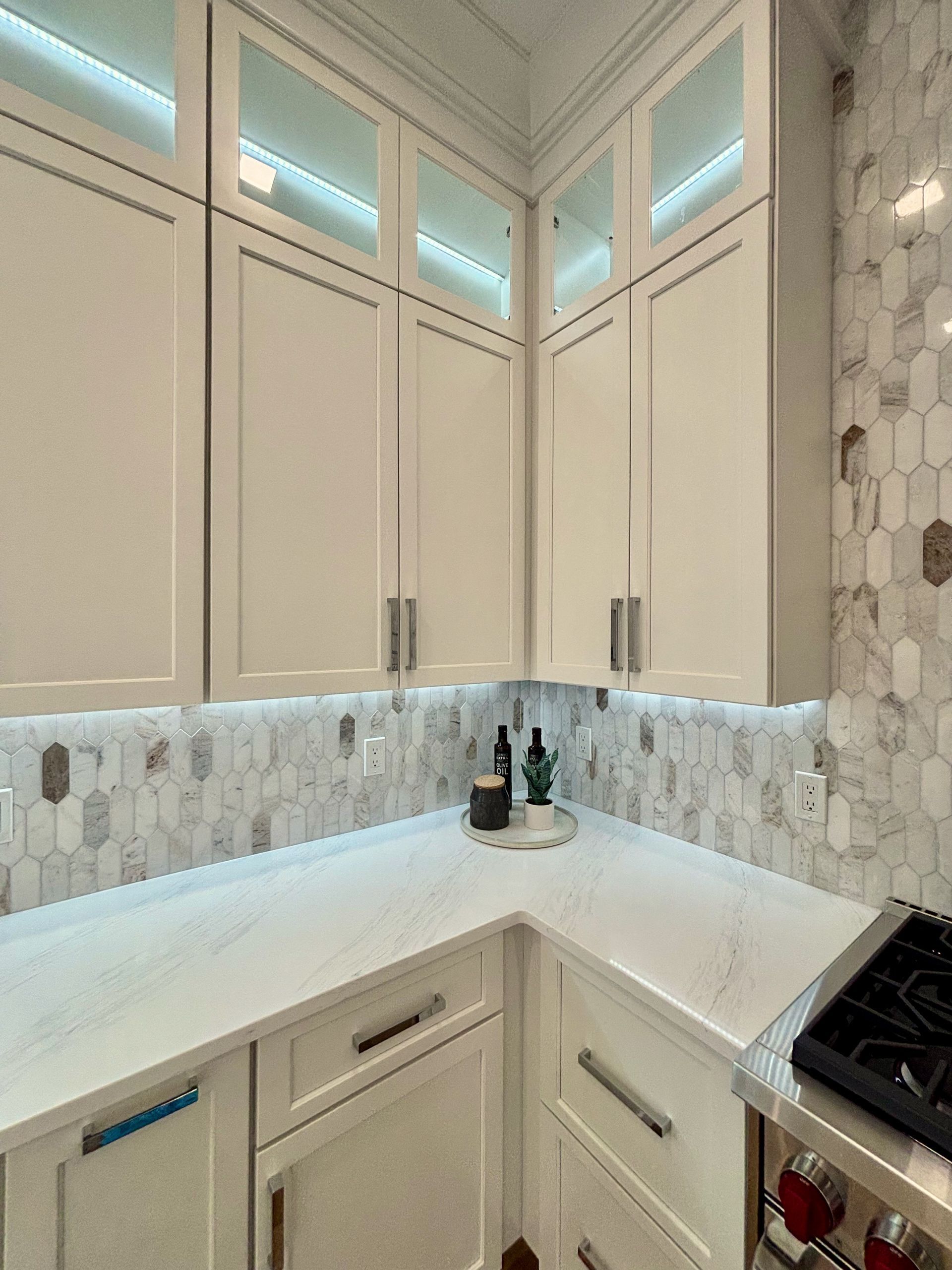 A kitchen with white cabinets and a stove top oven.