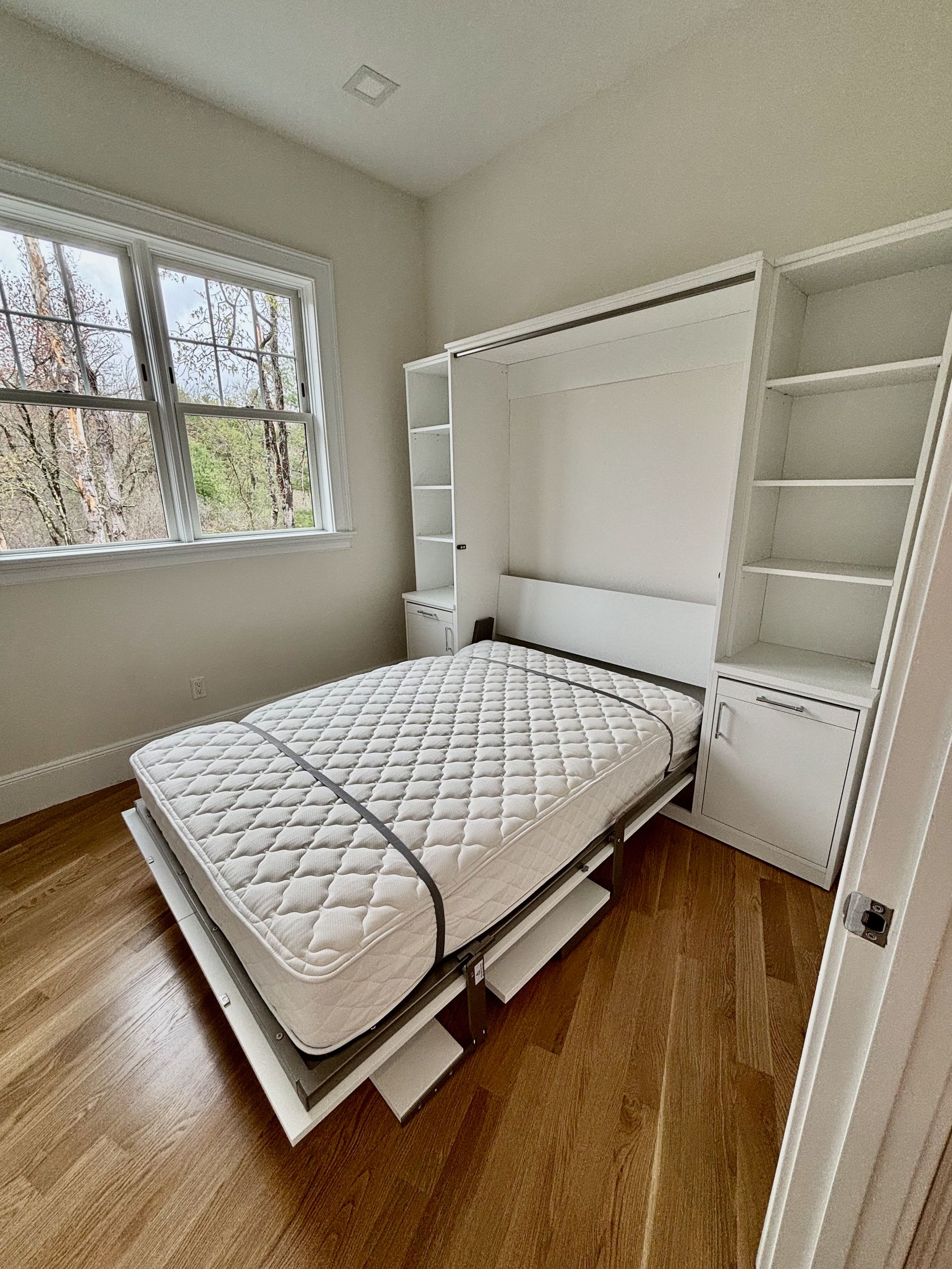 A bedroom with a bed , shelves , and a window.