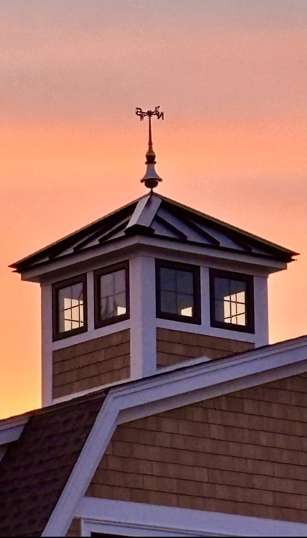 A weather vane on top of a building at sunset