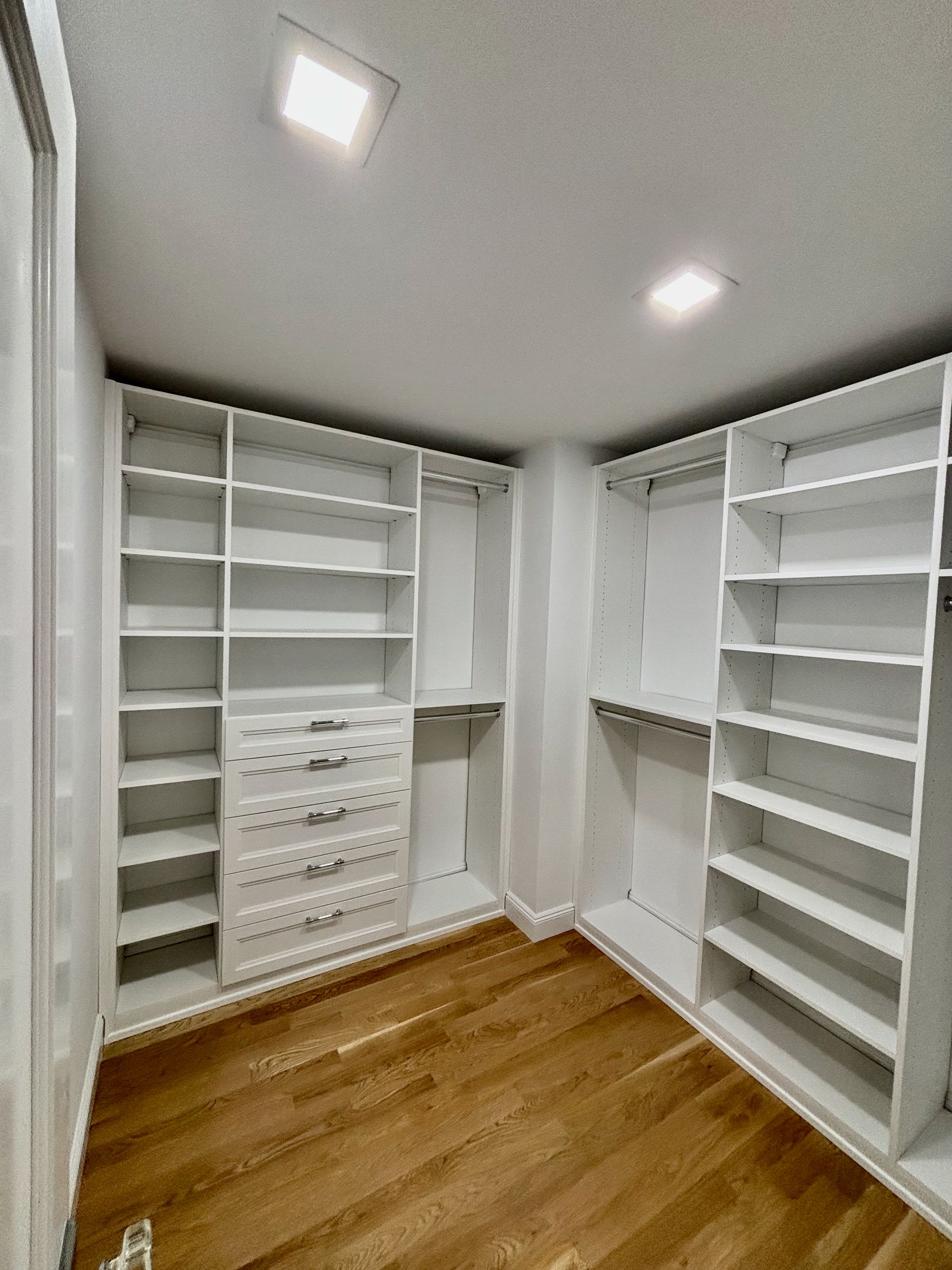 A walk in closet with lots of shelves and drawers