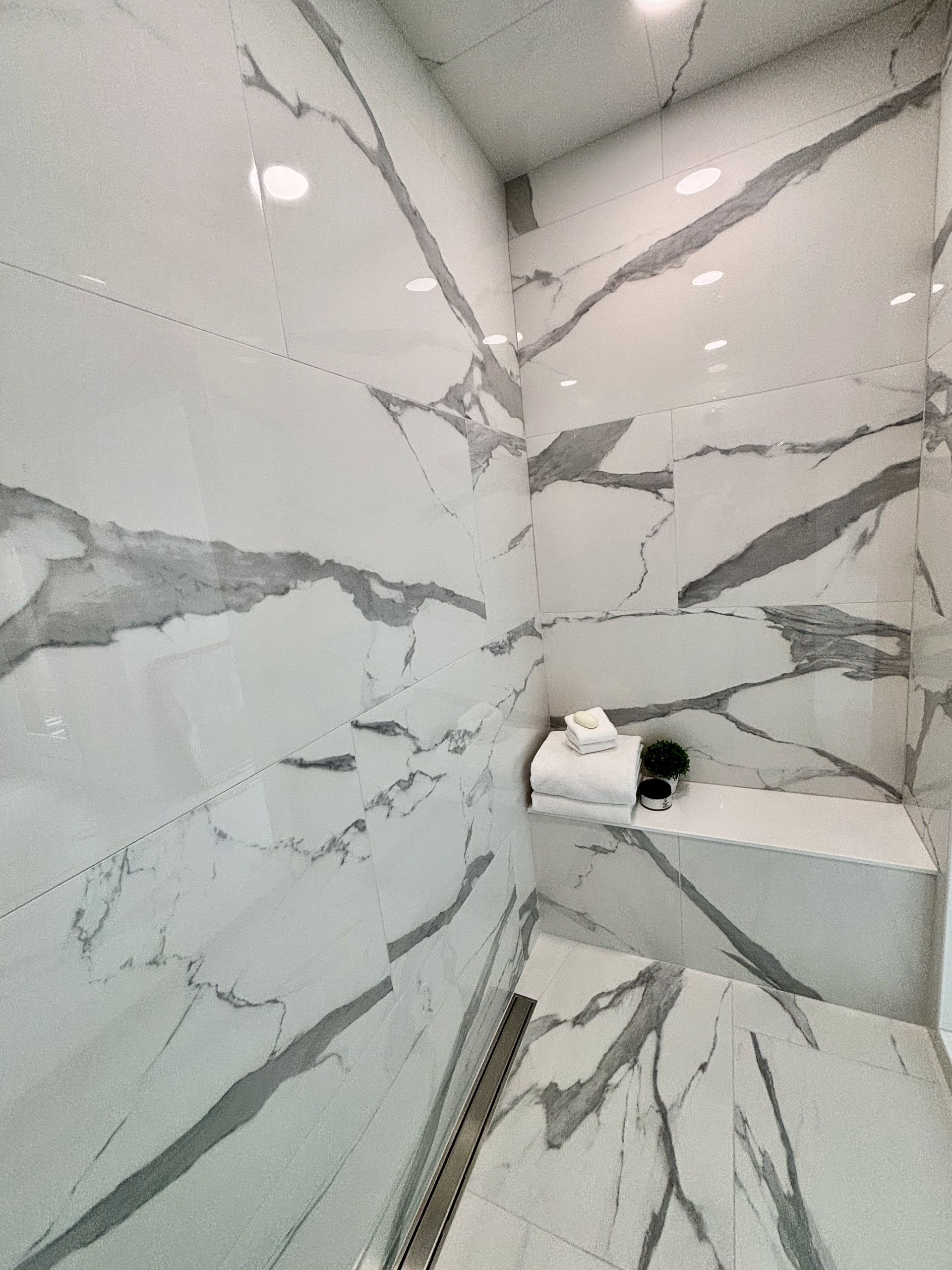 A bathroom with marble tiles and a walk in shower.